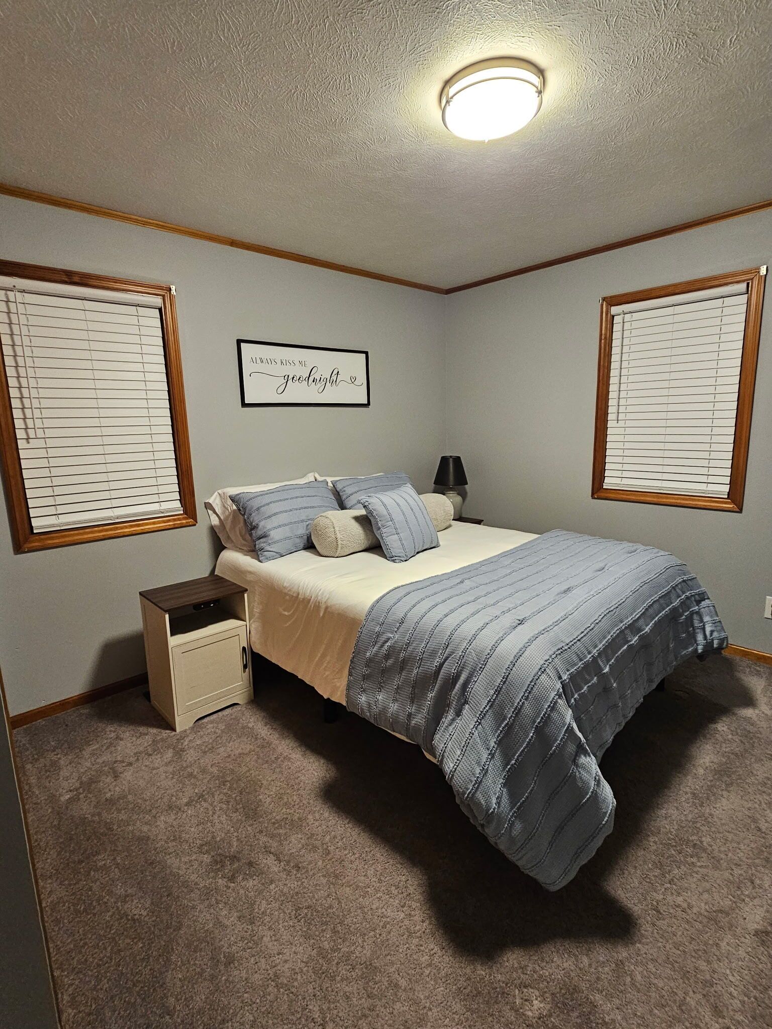 Une chambre à coucher comprenant un lit, une table de chevet, une lampe et un luminaire fixé au mur.
