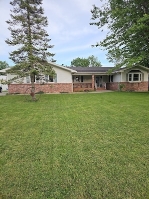 A two-story house with a front porch, a brick foundation, and a well-maintained lawn. - Spacious 4-bedroom house in quaint Lakeview with AC. Beautiful private back deck (Lakeview)
