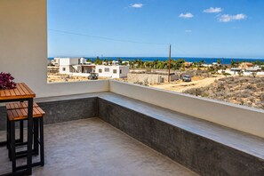 A balcony with a view of a coastal area, including buildings and a clear sky. - Dreamy desert villa: luxe pool & ocean views (Todos Santos)