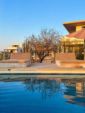Una piscina con acqua limpida che riflette il cielo e gli edifici circostanti.