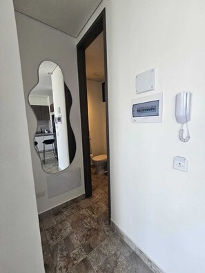 Ein Flur mit Spiegel, Telefon und Lichtschalter an der Wand.