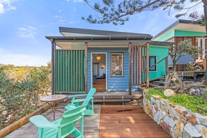 Une maison moderne dotée d’une terrasse en bois, d’un espace salon extérieur et d’un mur en pierre.