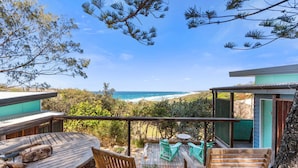 A wooden deck with outdoor seating, overlooking a beach and ocean. - The Headland Chalets - Cabin 3 (Point Lookout)
