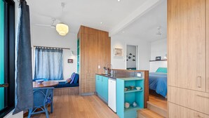 Un espacio habitable compacto con kitchenette, una zona de comedor con mesa y sillas, una sala de estar con sofá, y un dormitorio con cama.