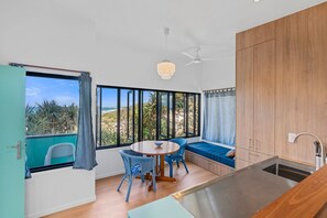 A modern kitchen with a large window, a dining area with a round table and chairs, and a built-in bench with a view of the outdoors.