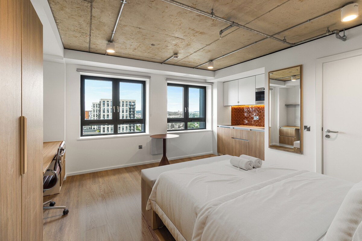 A modern bedroom with a large bed, a small table, and a mirror.