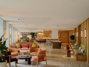 A spacious hotel lobby with a central bar area, seating arrangements, and a pool table. - Arthur House (Wembley)