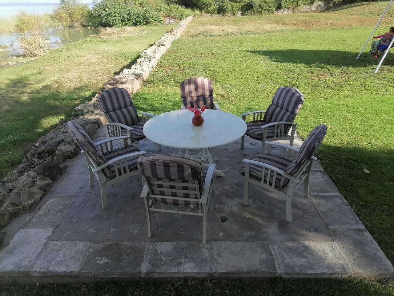 A patio with a round table and four chairs, surrounded by a concrete border.