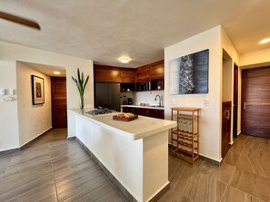 A modern kitchen with a central island, wooden cabinets, and a large painting on the wall. - Villa Coco - Private Pool, Ocean View, and Ixtapa Marina (Zihuatanejo de Azueta)