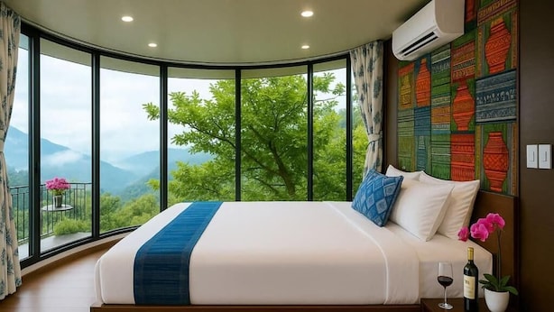 Une chambre dotée d’un grand lit, offrant une vue sur la verdure, et dont un mur est décoré d’œuvres d’art aux motifs originaux.