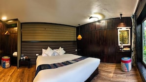 Une chambre à coucher avec un grand lit, des murs en bois, une fenêtre donnant sur un beau paysage et une table de chevet avec une lampe.