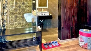 Une salle de bain avec une douche à parois de verre, un meuble-lavabo en bois et un tapis rouge sur le sol.