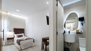 Un dormitorio con cama, mesita de noche y un pequeño escritorio con silla.