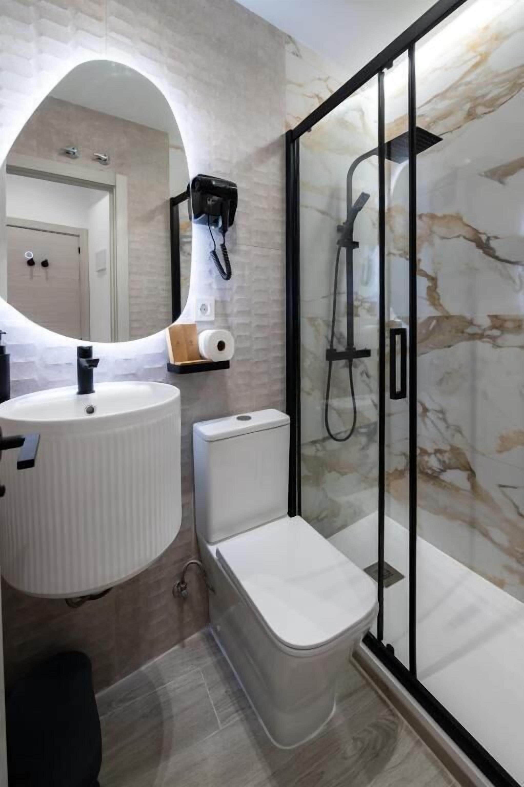 Een badkamer met een witte wastafel, toilet en douchecabine met glazen wanden.