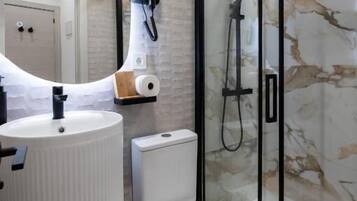Een badkamer met een witte wastafel, toilet en douchecabine met glazen wanden.
