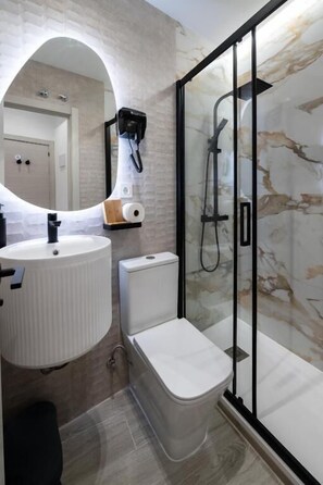 A bathroom with a white sink, toilet, and glass-enclosed shower.