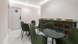 Una habitación con una mesa de comedor, cuatro sillas, un mueble con cestas y una puerta con el símbolo del número.