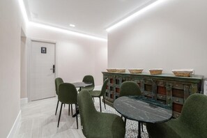 A room with a dining table, four chairs, a cabinet with baskets, and a door with a number sign. - Rosales Suites (Madrid)
