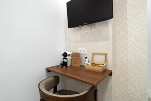 A small workspace with a desk, chair, coffee maker, and a box of tissues. - Rosales Suites (Madrid)