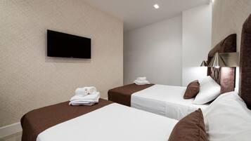 Een hotelkamer met twee bedden, een flatscreen televisie aan de muur en een spiegel met decoratieve lijst.