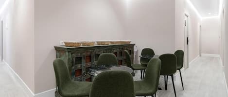 Un comedor con una mesa redonda y seis sillas, un aparador decorativo con cestas, y una alfombra estampada.