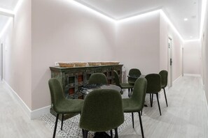 A dining area with a round table and six chairs, a decorative cabinet with baskets, and a patterned rug. - Rosales Suites (Madrid)
