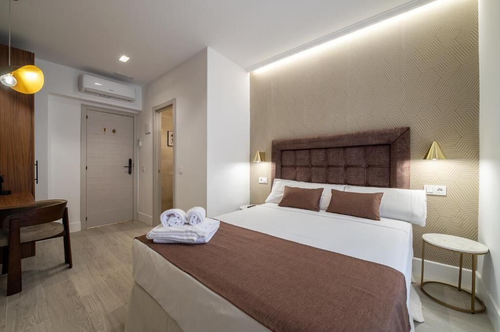 A hotel room with a bed, bedside tables, a desk, and a chair.