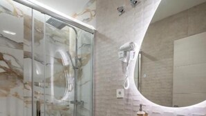 Un baño moderno con cabina de ducha de vidrio, inodoro, lavabo con una pileta grande y espejo.