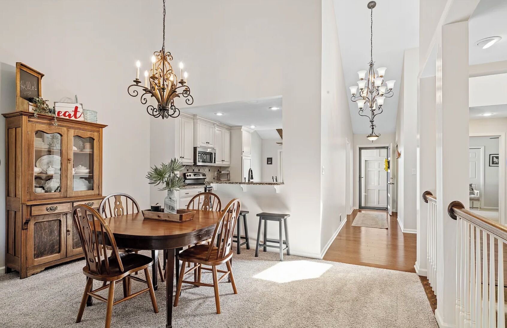 Un coin repas avec une table et des chaises en bois, un lustre et un buffet aux portes vitrées.