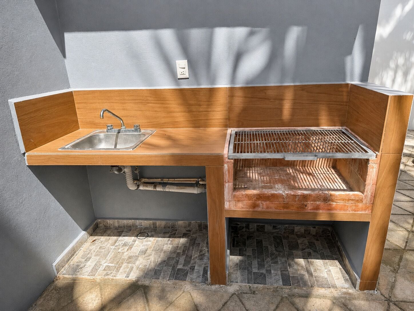 Eine kleine Außenküche mit Spüle, Grill und integriertem Schrank.