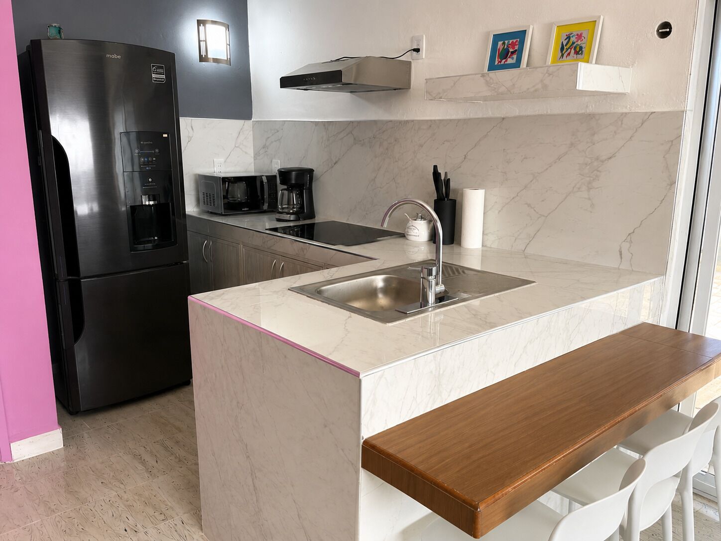 A modern kitchen with a built-in refrigerator, a microwave, a coffee maker, and a sink.