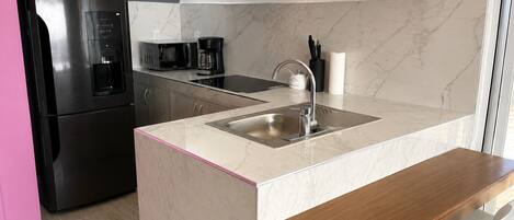 A modern kitchen with a built-in refrigerator, a microwave, a coffee maker, and a sink.