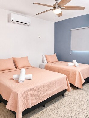 Ein Hotelzimmer mit zwei Betten, einer Klimaanlage, einem Deckenventilator und einer Projektionsleinwand an der Wand.