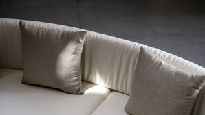 Un sofá moderno y curvo con tela de color claro y dos almohadas.