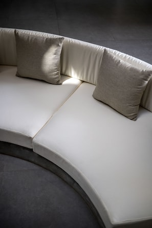 Un sofá moderno y curvo con tela de color claro y dos almohadas.
