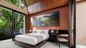Un dormitorio moderno con una cama grande, un cuadro de un paisaje, una silla y una mesita de noche.