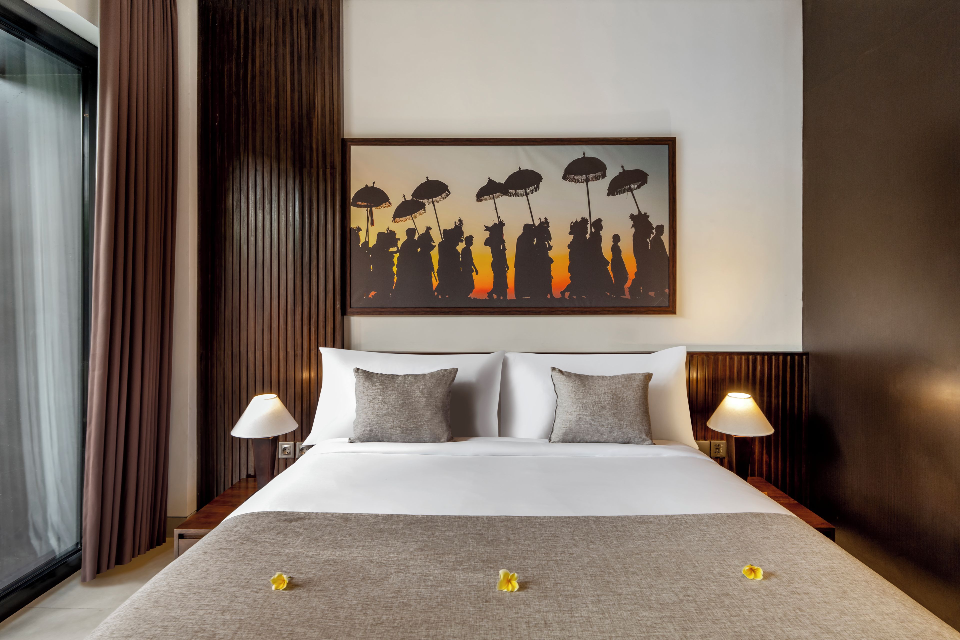 Habitación de hotel con una cama grande, dos lámparas de noche, un cuadro en la pared y una ventana con cortinas.