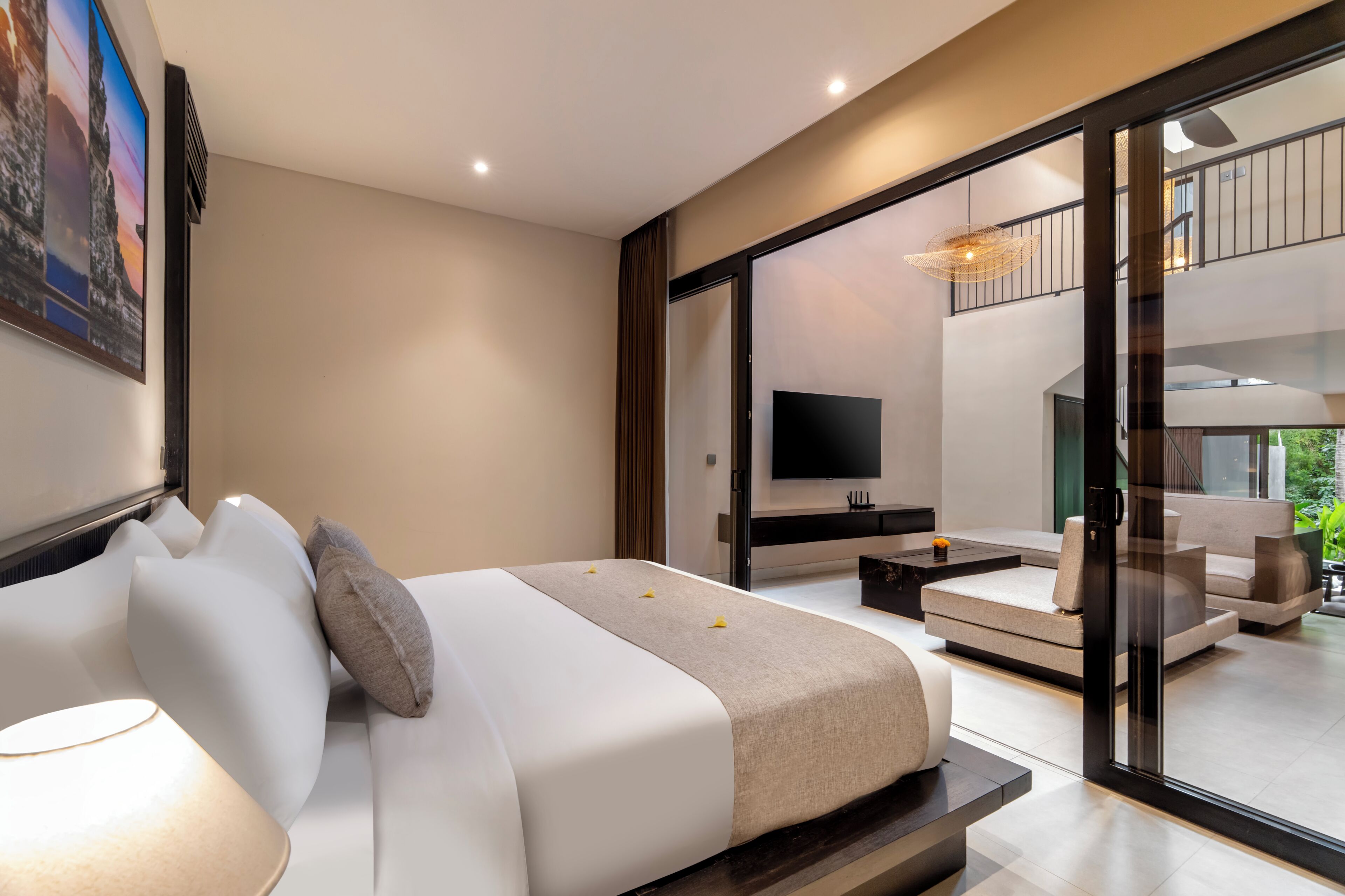 A modern bedroom with a bed, a TV, and a balcony with seating.