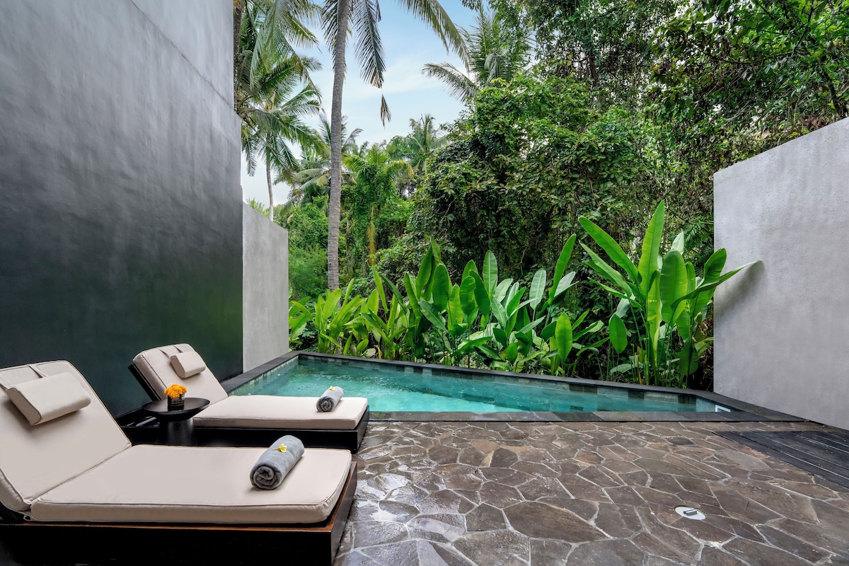 Un área de piscina moderna al aire libre con sillones de descanso y suelo de piedra.