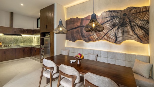 Un comedor moderno con una mesa y sillas de madera, una gran obra de arte abstracto en la pared e iluminación colgante.