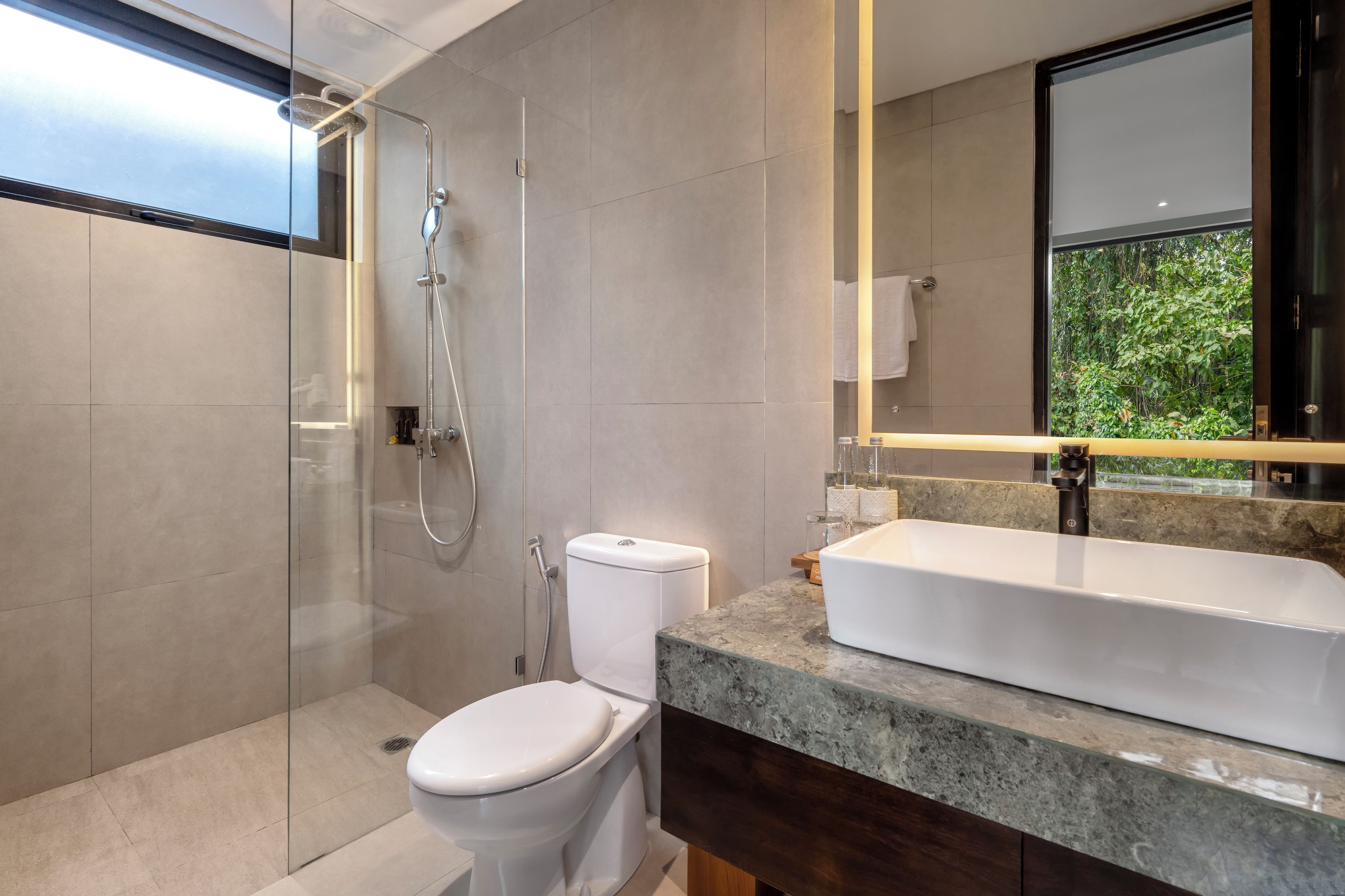 Een moderne badkamer met een douche met glazen wand, een toilet en een ruime badkuip.