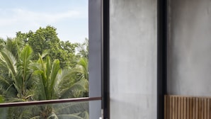 Un dormitorio moderno con balcón y vistas a un jardín tropical.
