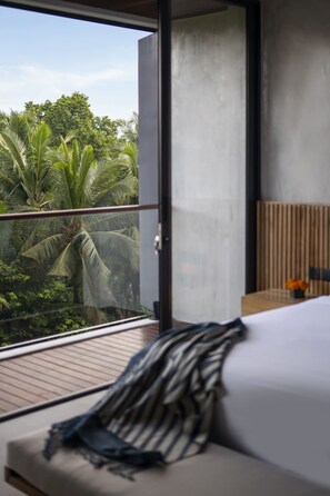 Un dormitorio moderno con balcón y vistas a un jardín tropical.