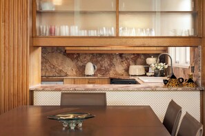 A modern kitchen with a marble countertop, a built-in oven, and a dishwasher. - Sol Haus | Hot Tub, Volleyball & Fireside Nights (Wentworth Falls)