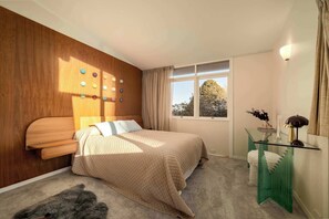 A bedroom with a bed, a bedside table, a window, and a wall with circular decorations. - Sol Haus | Hot Tub, Volleyball & Fireside Nights (Wentworth Falls)