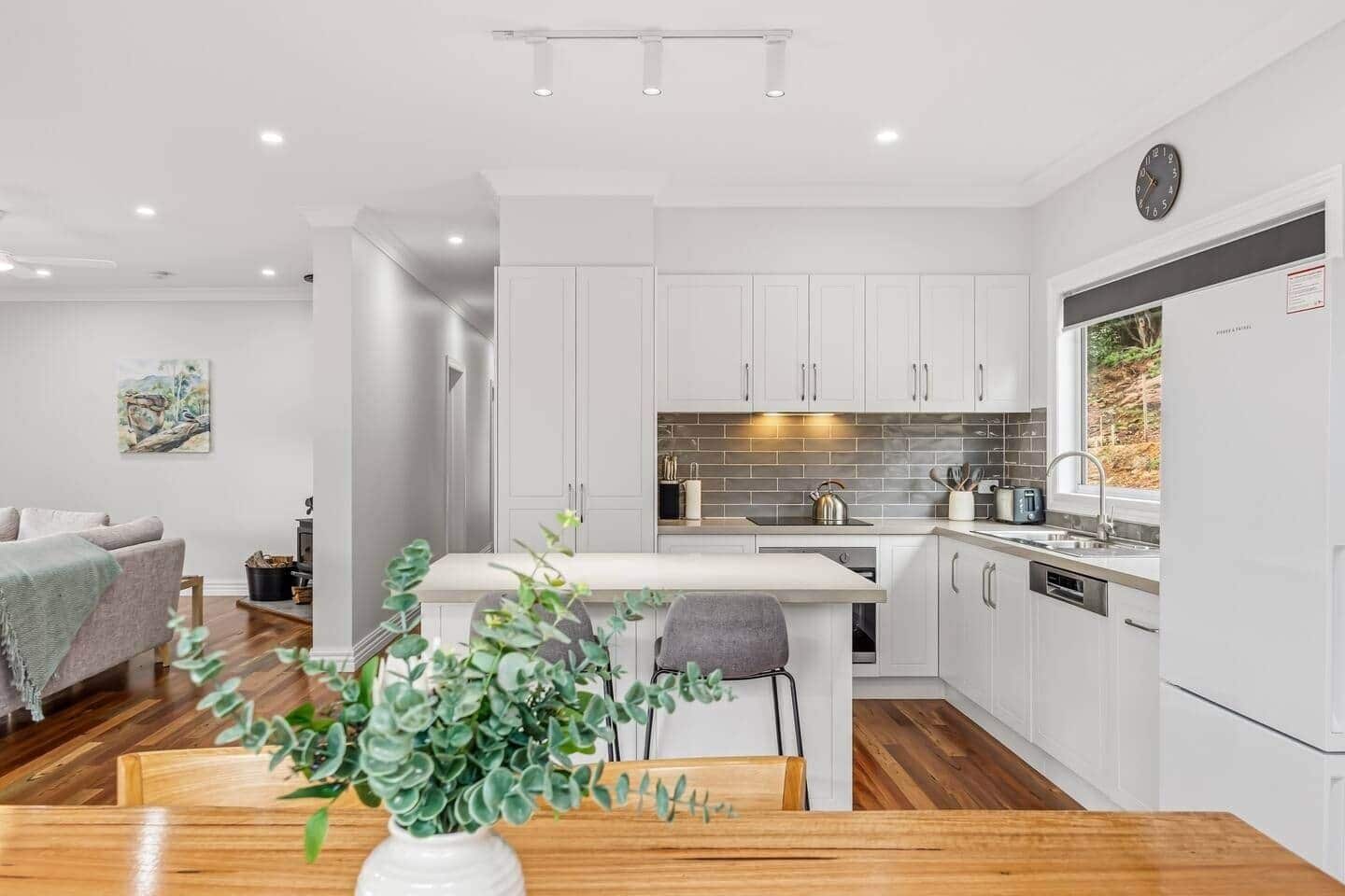 A modern kitchen with white cabinets, a wooden countertop, and a built-in oven.