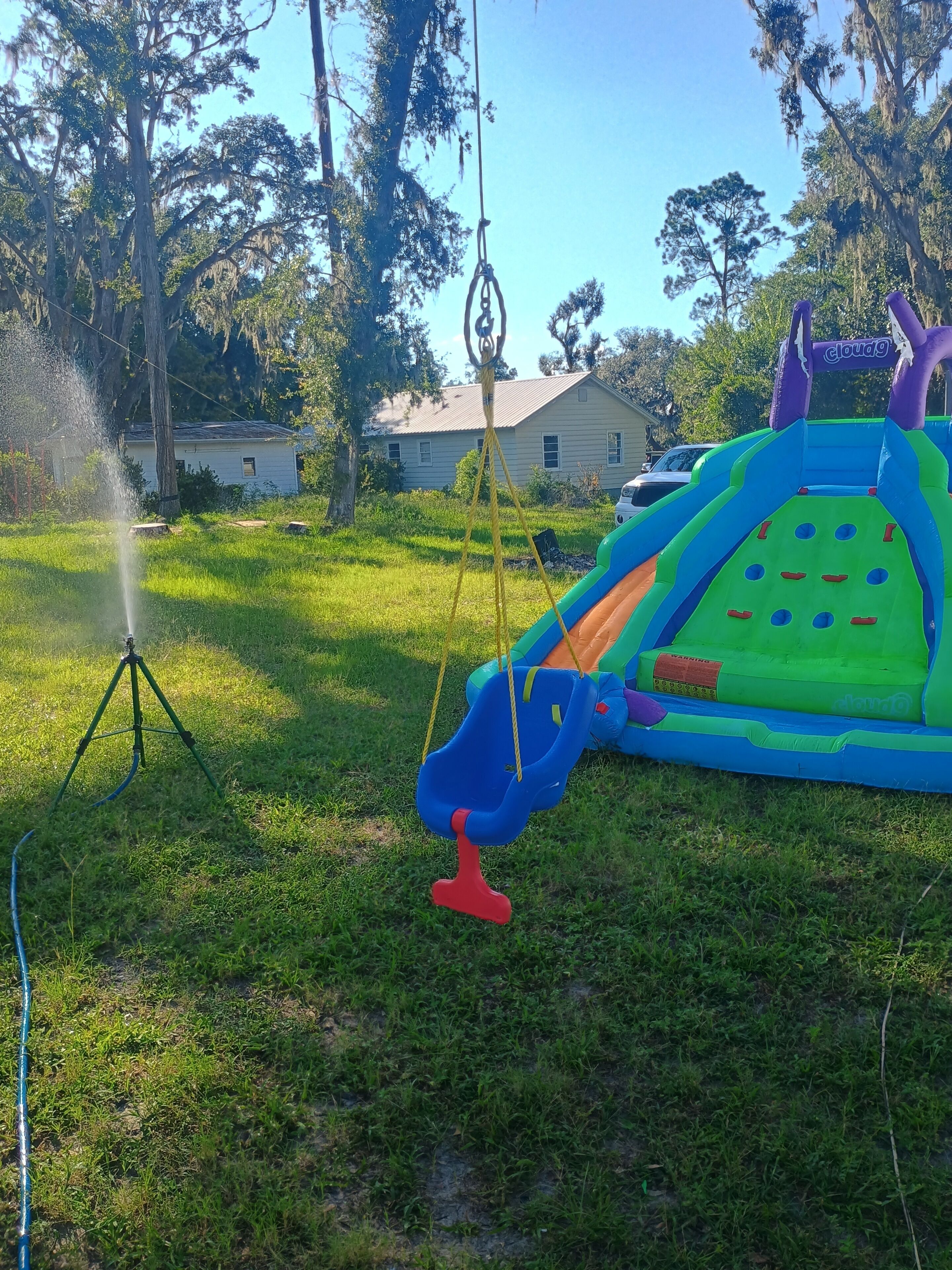 A grassy outdoor area with a swing set and a colorful inflatable play structure.