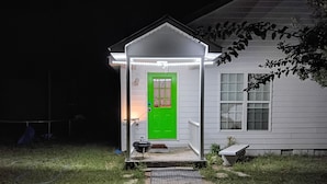 A house with a green door, a porch, and a small shed with a barbecue grill.