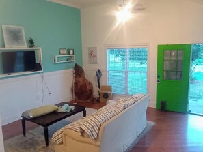 Een woonkamer met een bank, een salontafel, een televisie en een groene deur.