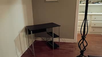 A room with a black desk, a white dresser, and a floor lamp.